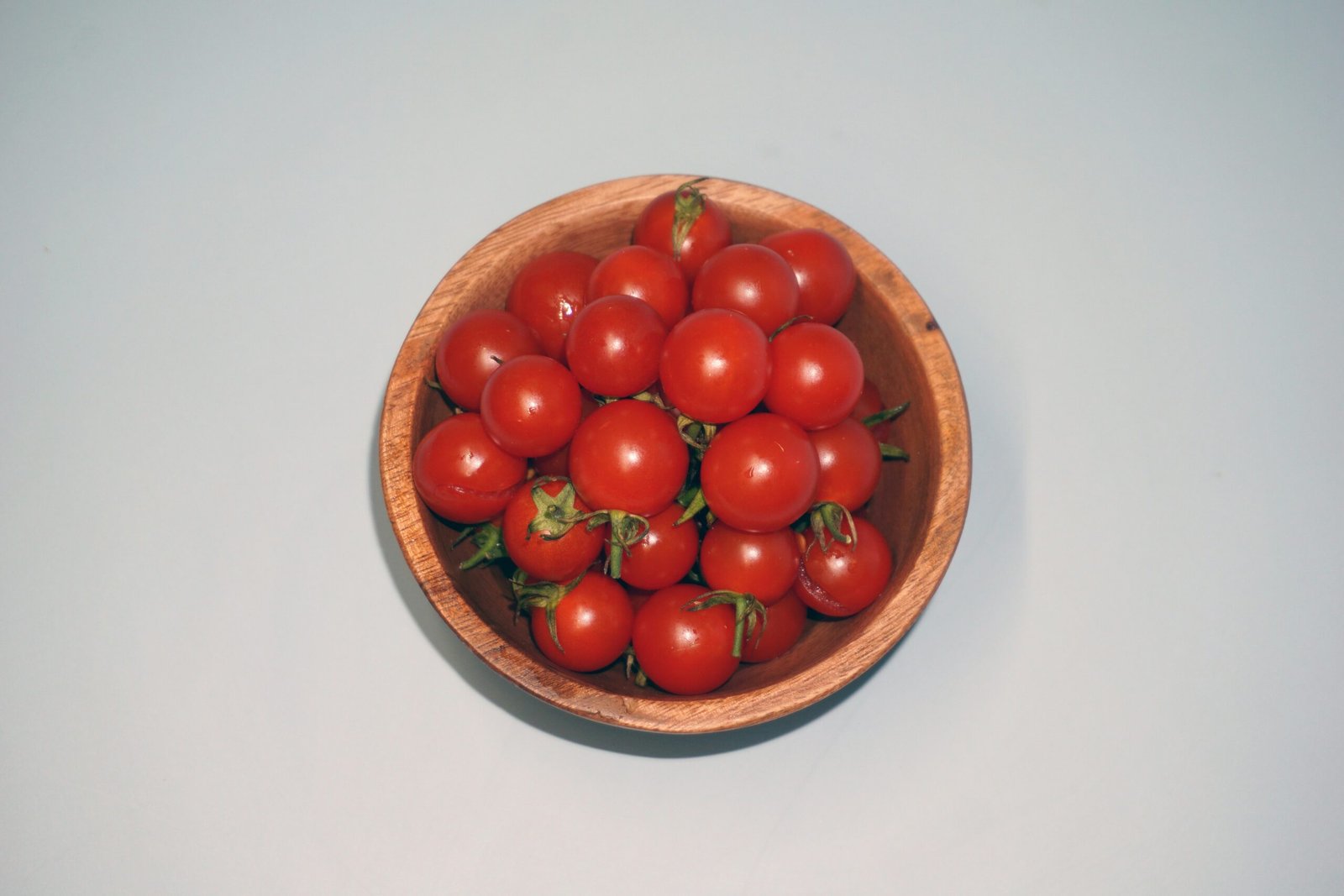 a wooden bowl filled with lots of red tomatoes